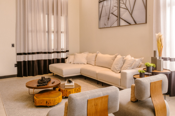 Modern minimalist living room featuring a cream sectional sofa, wooden coffee tables, and contemporary decor.