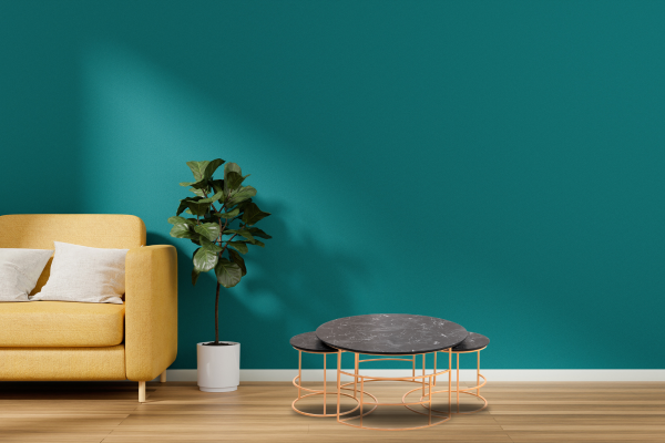 Modern living room with a yellow sofa, black marble coffee tables, and a fiddle leaf fig plant against a teal wall.